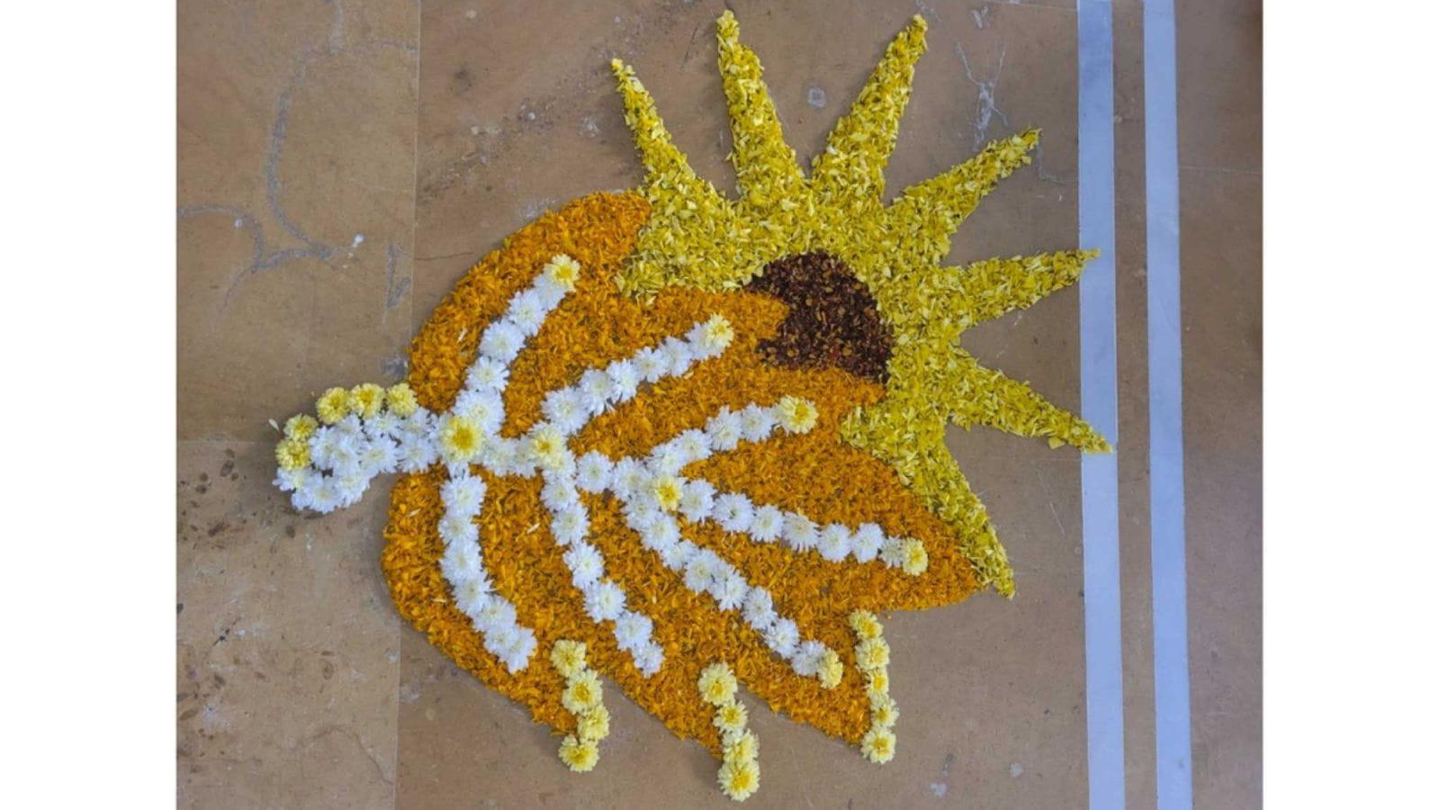 A design of a leaf and sun made from orange, white and yellow flowers and petals